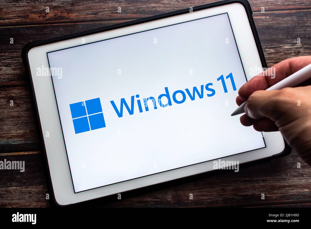 Kumamoto, JAPAN - Jun 25 2021 : Windows 11 logo on tablet on table. It is major release of the Windows NT operating system by Microsoft. Man holds pen Stock Photo