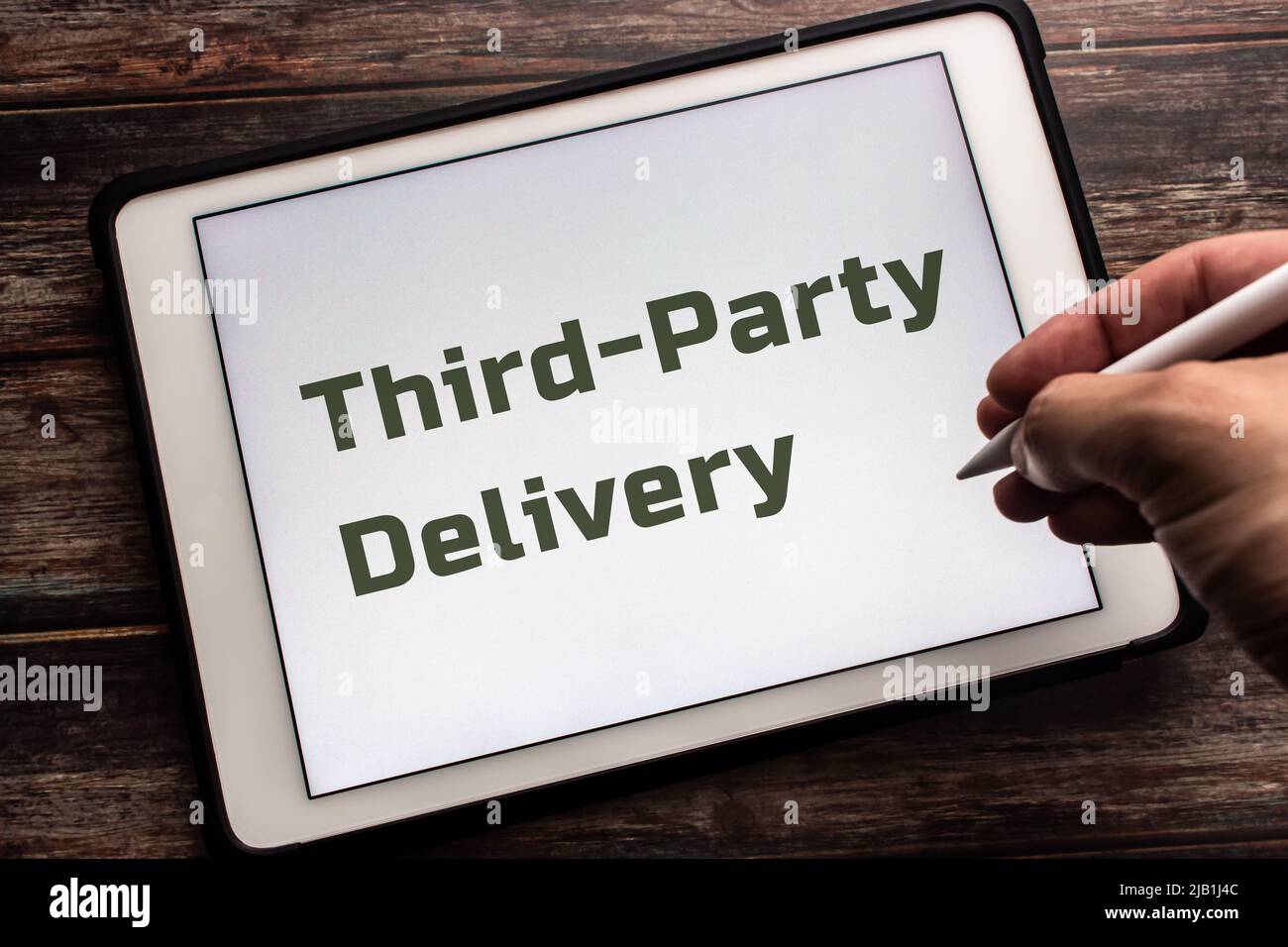 Closeup keyword Third-Party Delivery on tablet. Outsourcing delivery to a 3rd-party company and paying them a fee concept. Man holding stylus pen Stock Photo