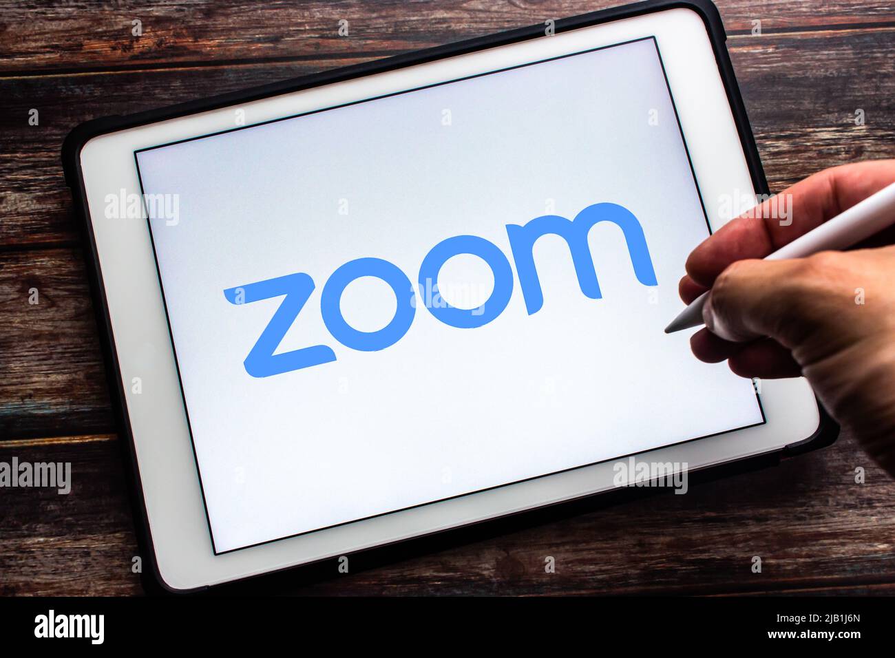 Kumamoto, JAPAN - Jul 21 2021 : Logo of Zoom app, video & online chat service by US company Zoom Video Communications, Inc., on tablet. Man holds pen Stock Photo