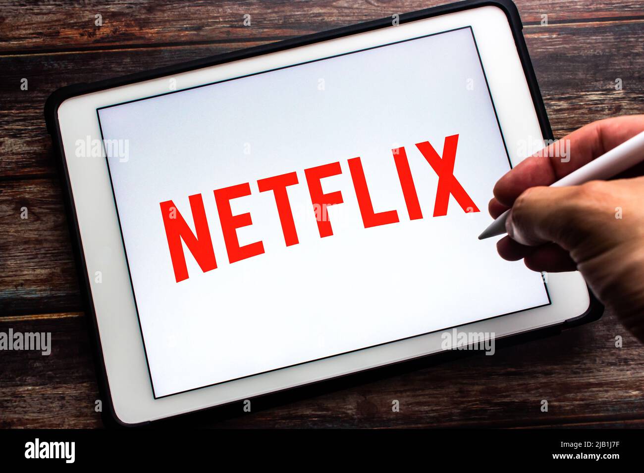 Kumamoto, JAPAN - Jul 21 2021 : Logo of Netflix, an US media-services provider company based in Los Gatos, CA, on tablet. Man hand holding stylus pen Stock Photo