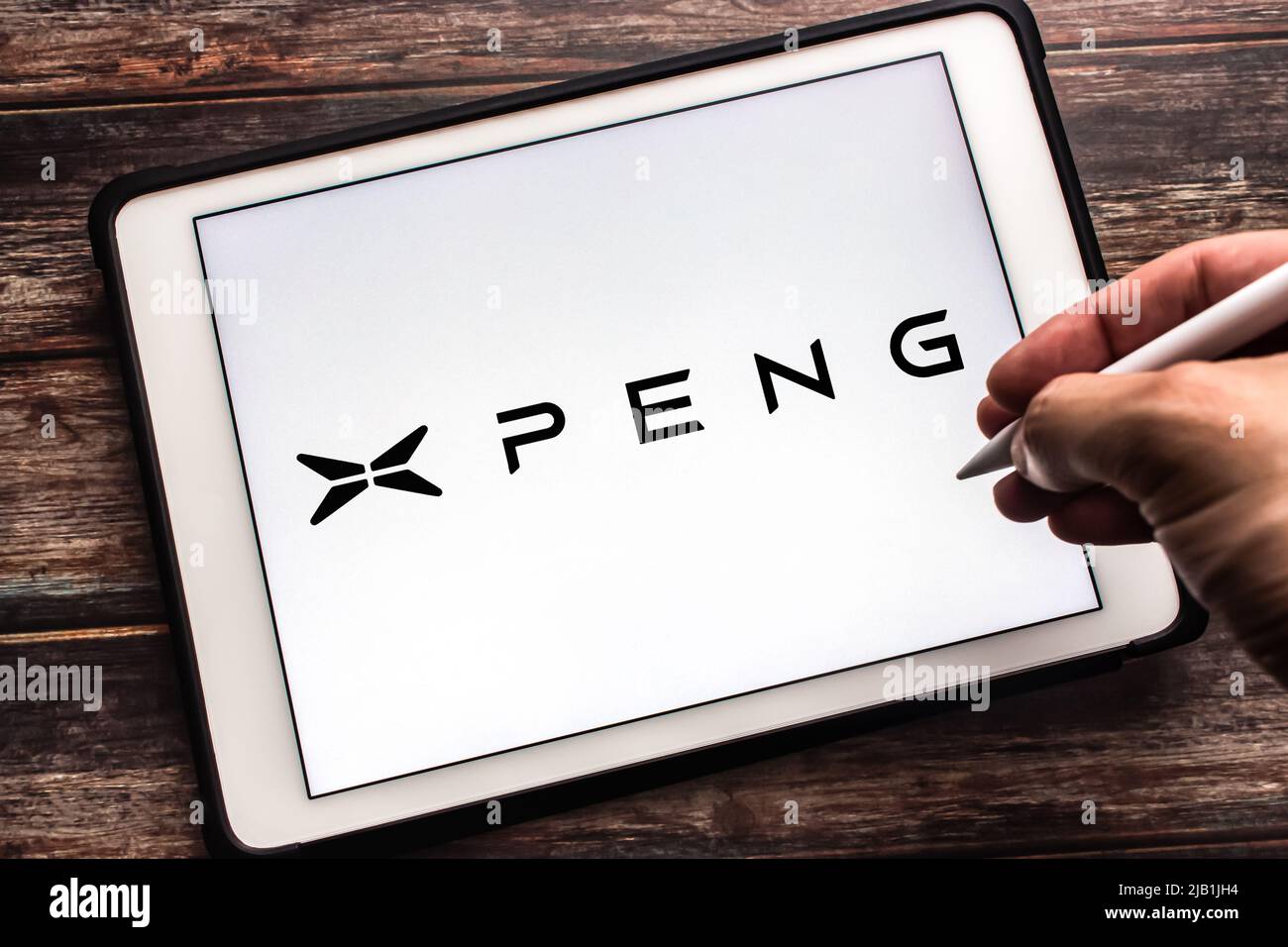 Kumamoto, JAPAN - Jul 27 2021 : Logo of Chinese electric vehicle brand Xpeng (Guangzhou Xiaopeng Motors, XMotors.ai) on tablet. Man holds pen Stock Photo