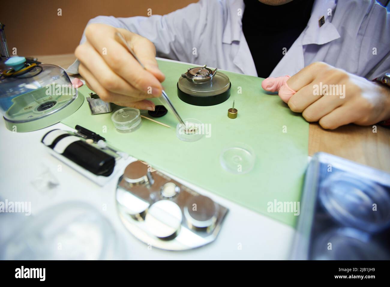 Close-up of unrecognizable laboratory engineer using tweezer to take small cogs while assembling wristwatch Stock Photo