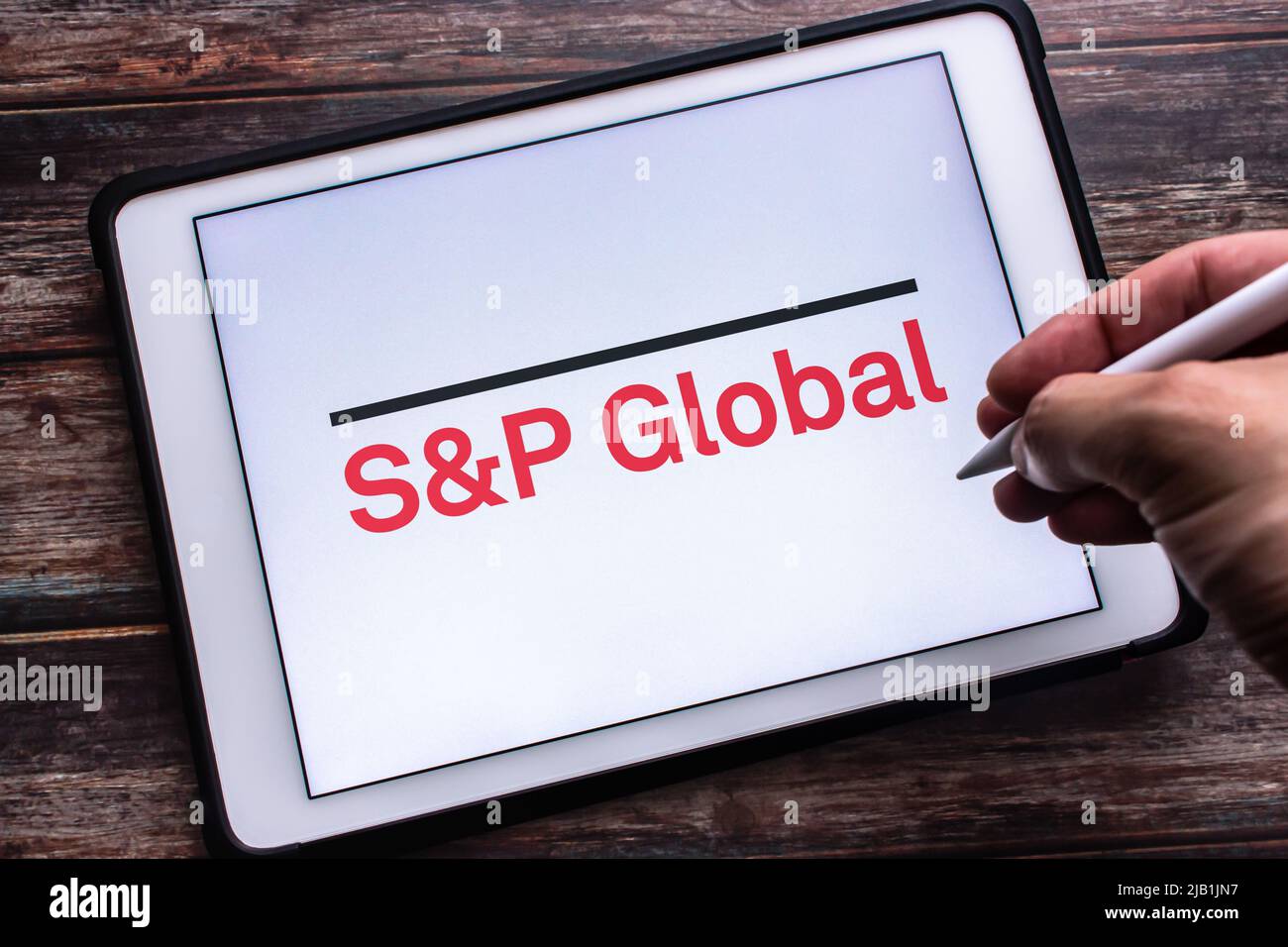 Kumamoto, JAPAN - Jul 30 2021 : Logo of S&P Global Inc., US traded corporation specialized in finance and analytics, on tablet. Man holding pen Stock Photo