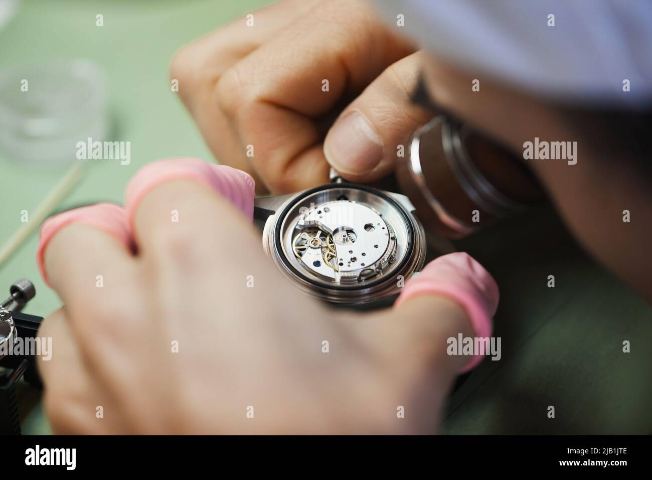 Close-up of unrecognizable engineer winding up clock while checking motion of watch mechanism Stock Photo