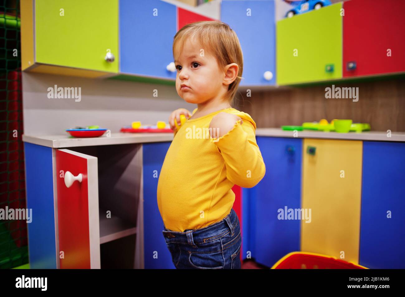 Cute baby girl playing in indoor play center. Kindergarten or preschool