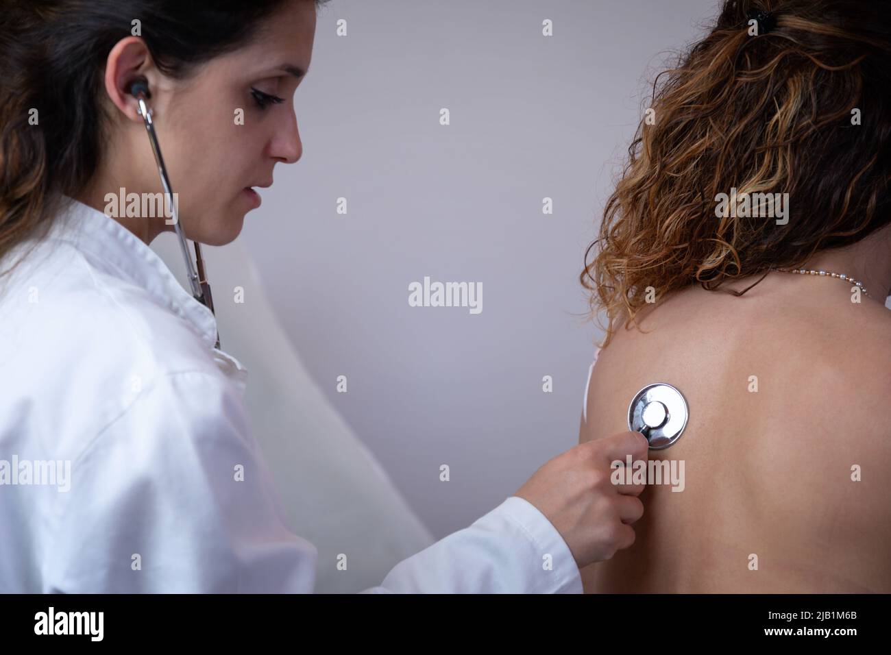 Doctor listens to the patient's chest with a stethoscope, observing the