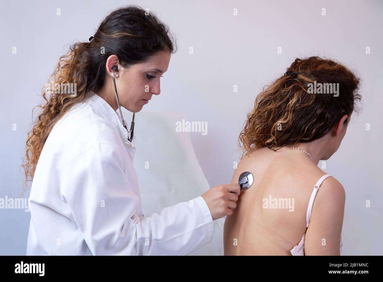 Doctor listens to the patient's chest with a stethoscope, observing the breathing and internal noises of the organism. Traditional medical examination Stock Photo