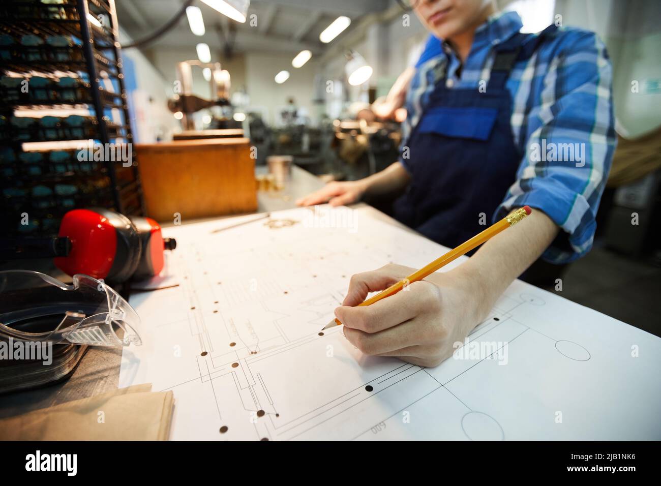 Close-up of busy engineer standing at desk and making points on technical card while working at factory Stock Photo