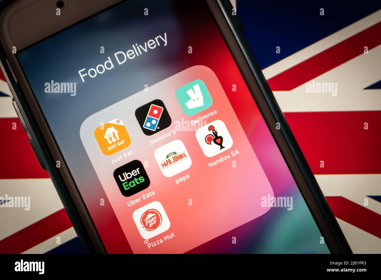 Kumamoto, JAPAN - Aug 16 2021 : UK food deli apps (Just Eat, Domino’s, Deliveroo, Uber Eats, Pizza Hut, Papa John’s and Nando’s) on iPhone on UK flag Stock Photo