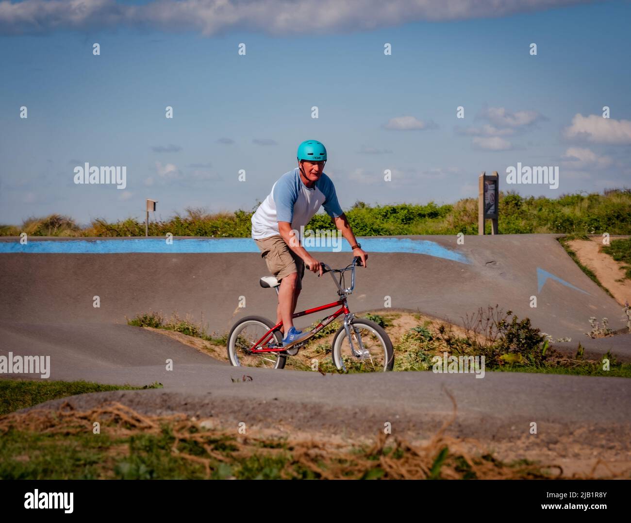 Merville, France, May 2022. Man with a helmet riding a BMX bike in the skate park. Sunny day, relaxation, sports lifestyle Stock Photo