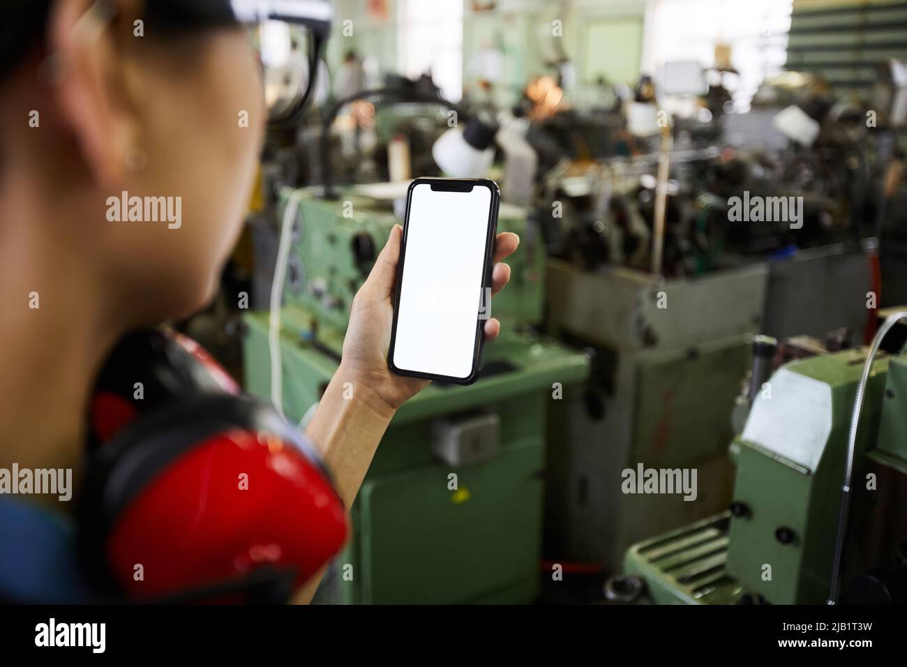 Close-up of engineer woman using smartphone while photographing workplace of factory shop Stock Photo