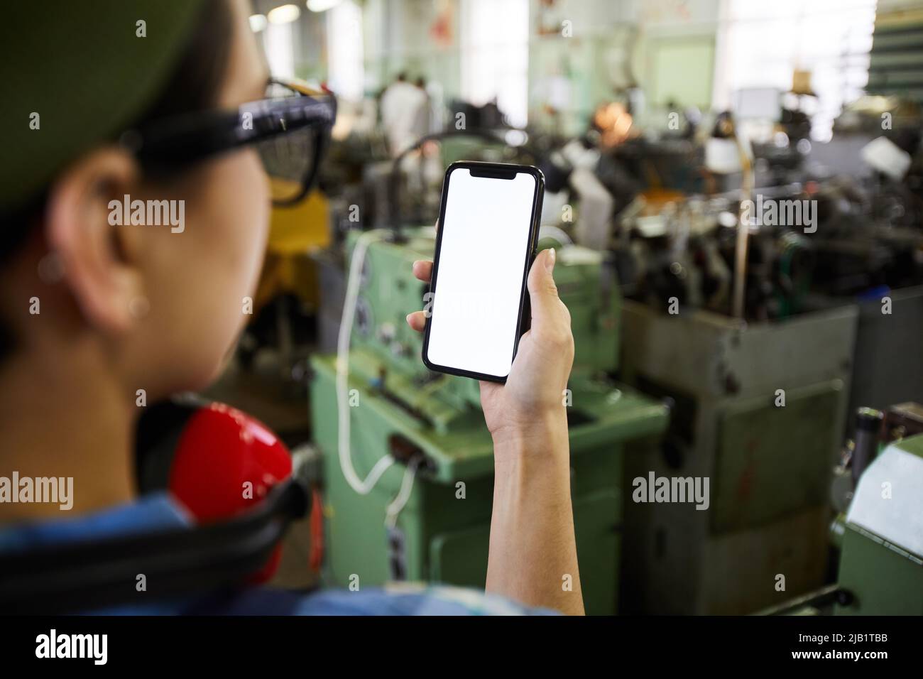 Close-up of busy lady engineer using mobile app in industry while working in factory shop Stock Photo