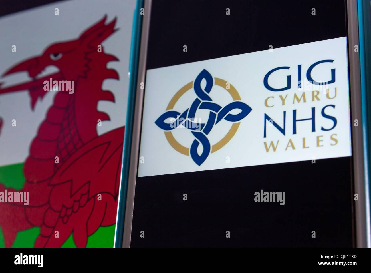 Kumamoto, JAPAN - Sep 6 2021 : Closeup logo of NHS Wales (Welsh: GIG Cymru), the publicly funded healthcare system in Wales, on iPhone on Welsh flag. Stock Photo