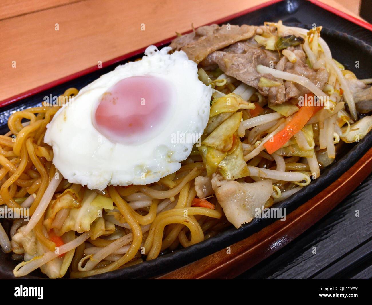 Japanese fried noodle Yakisoba with medamayaki (fried egg) plate. Yakisoba is a frying ramen-style wheat noodles with bite-sized porks & vegetables Stock Photo