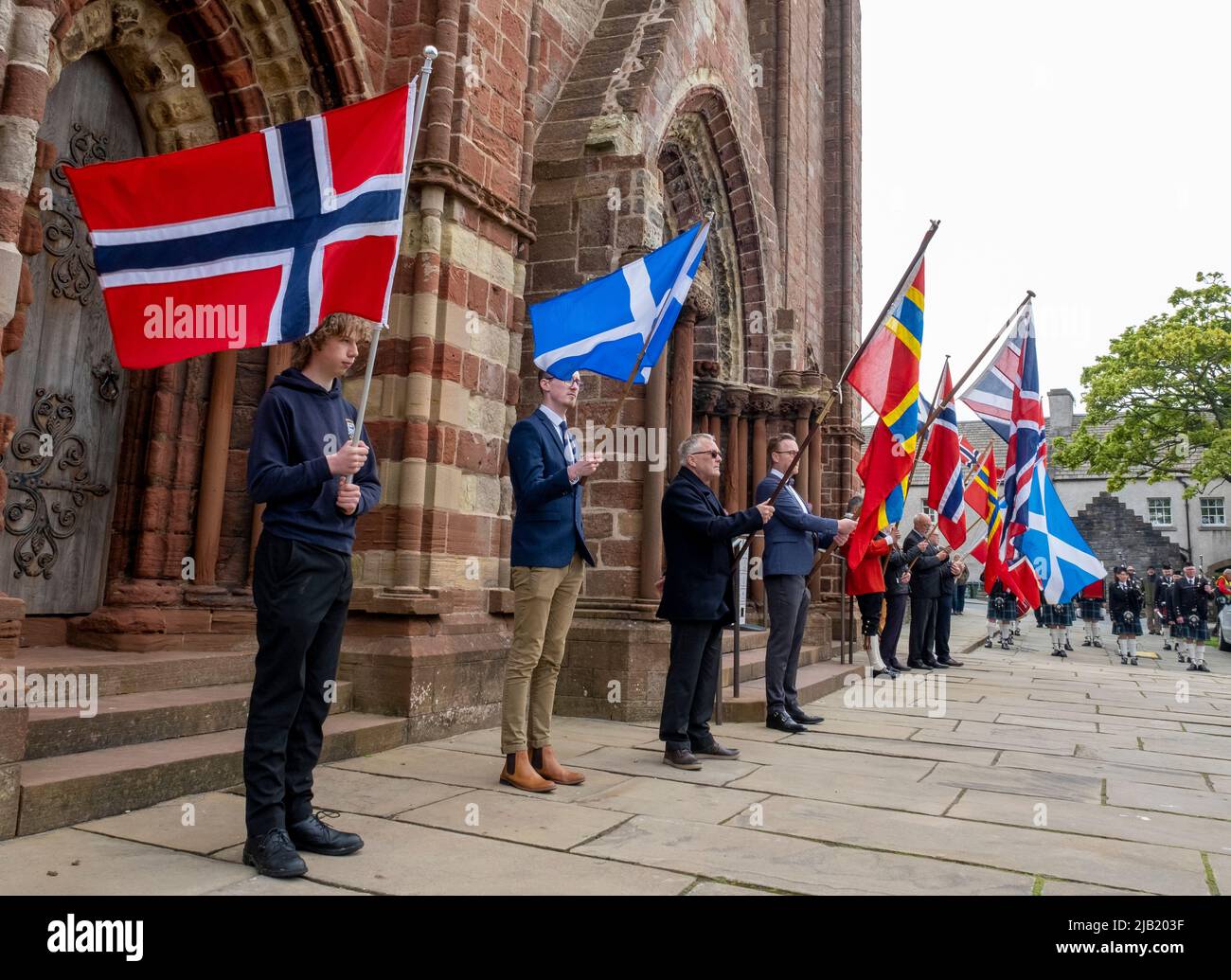 Flag bearers hold up the flags of Norway and Scotland outside St Magnus Cathedral to celebrate Norway Day in Kirkwall town centre, Orkney islands, Sco. Stock Photo