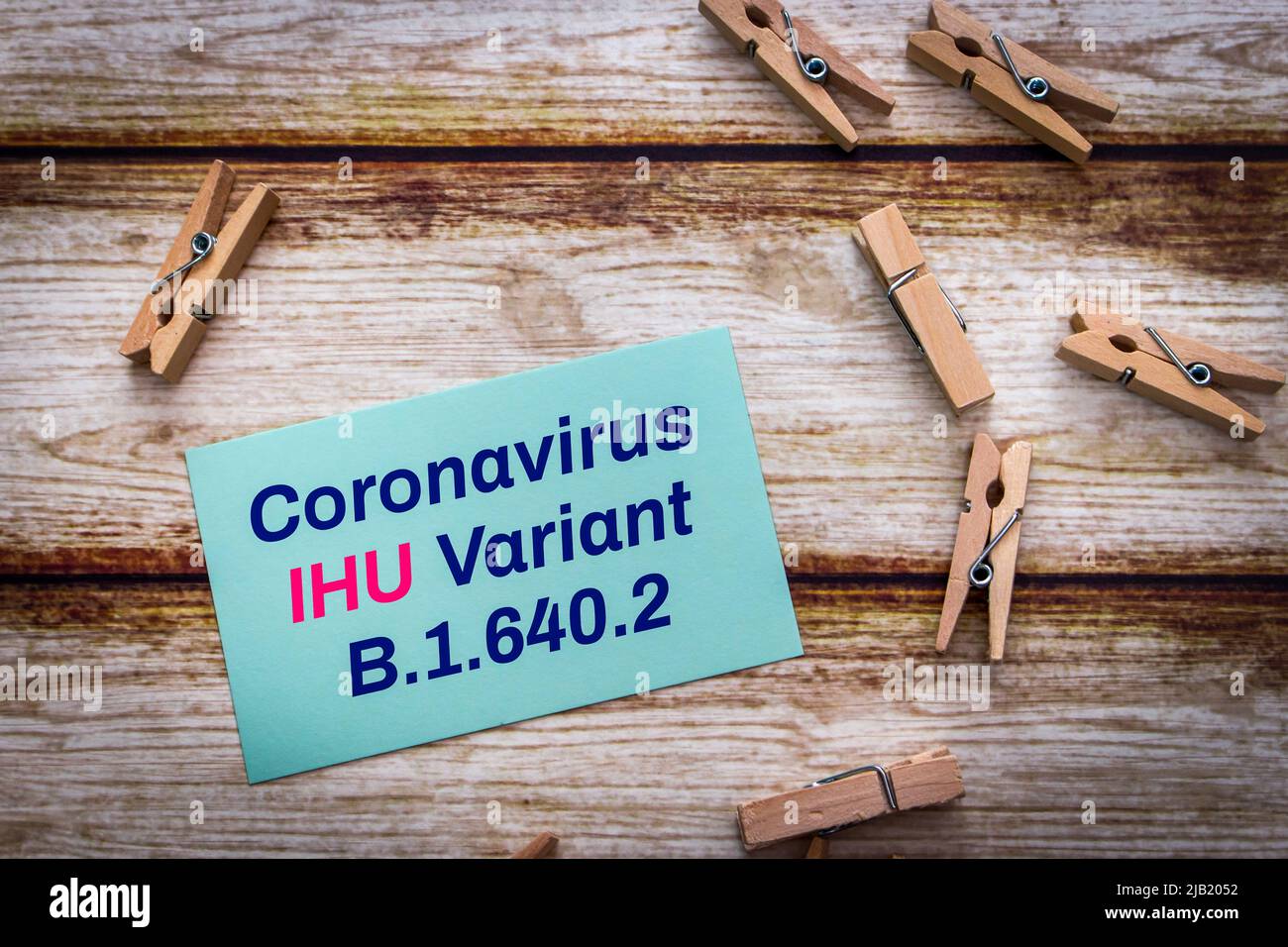 Message card showing Coronavirus IHU Variant B.1.640.2 with wooden pinch on shabby chic table. New COVID-19 variant detected in southern France Stock Photo