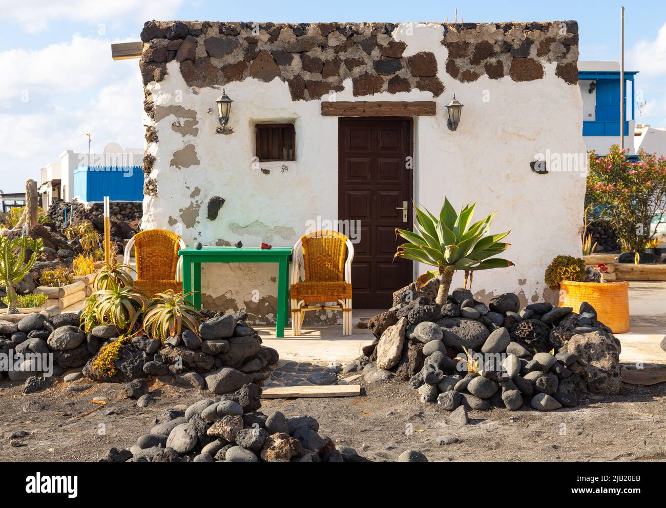 a typical tiny stone house at a coast of a fishing village on Lanzarote with big black pebble stone in front of it Stock Photo