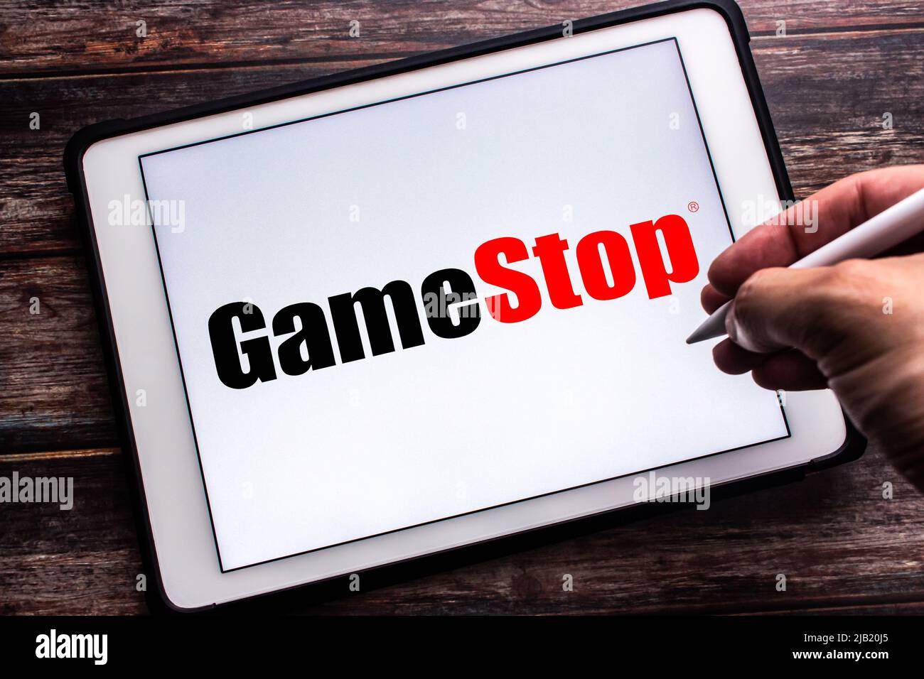 Kumamoto, JAPAN - Jan 21 2022 : Logo of GameStop Corp., an US video game, consumer electronics, & gaming merchandise retailer on tablet. Man holds pen Stock Photo
