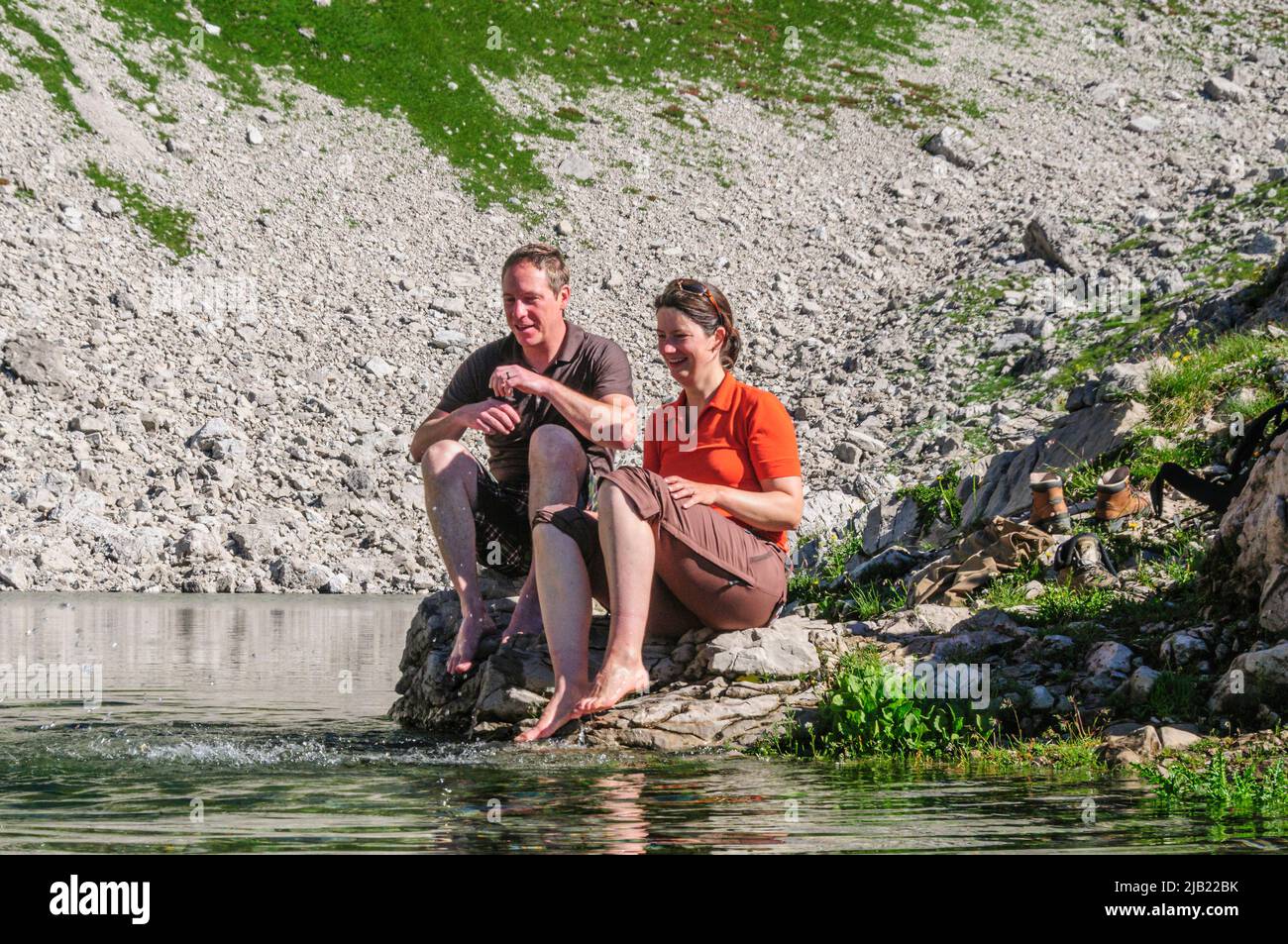 Couple enjoying morning sun while sitting at the Koblatsee near the Nebelhorn in Allgäu Alps Stock Photo