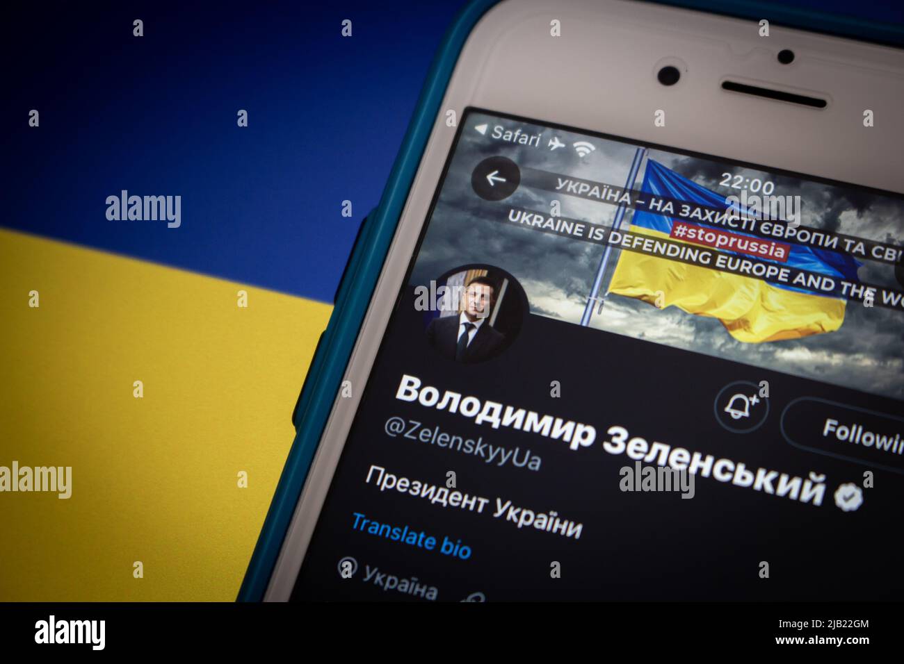 Twitter account of Volodymyr Zelenskyy, the 6th & incumbent president of Ukraine (former actor & comedian), on iPhone on an Ukraine flag in dark mood Stock Photo