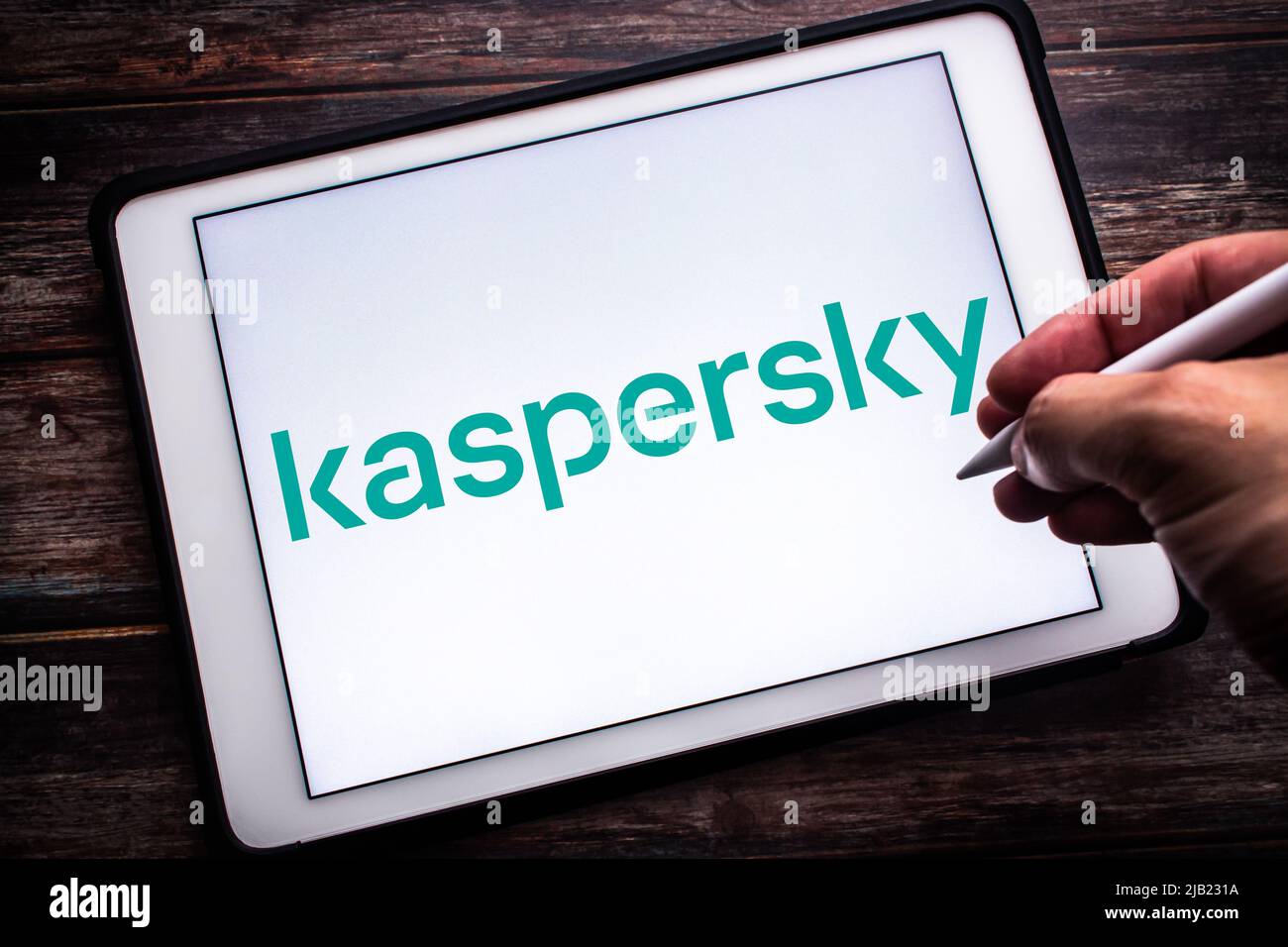 Kumamoto, JAPAN - Apr 12 2021 : Logo of a Russian cybersecurity and anti-virus provider Kaspersky Lab on tablet on the wooden table. Man holding a pen Stock Photo