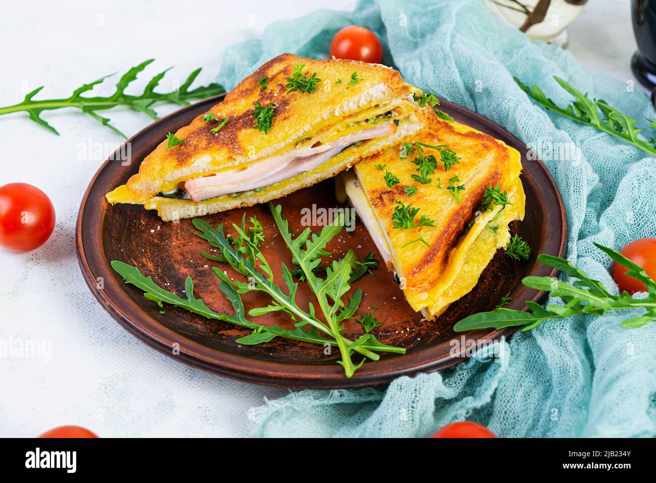 Roasted toast in scrambled eggs with ham, herbs and cheese cheddar. Delicious grilled breakfast