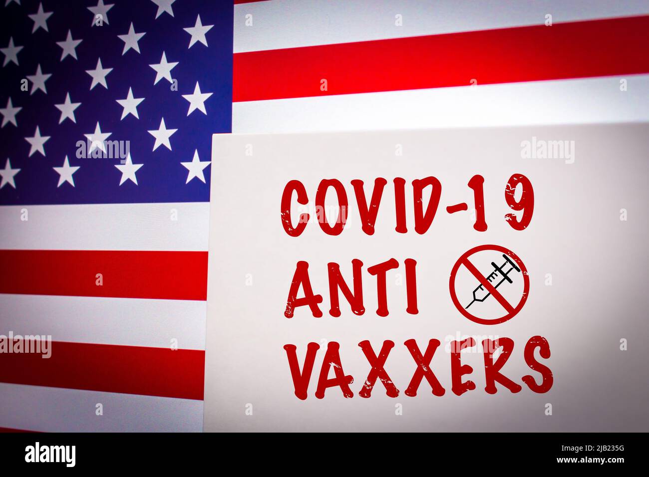 Conceptual keyword COVID-19 ANTI VAXXERS on card on an US flag background. Anti coronavirus vaccination concept. Stock Photo