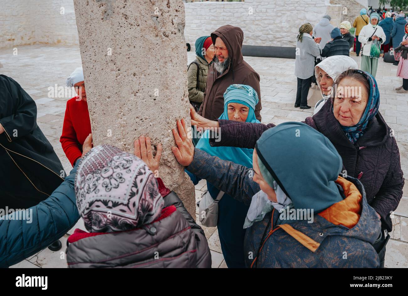 Bolgar, Tatarstan, Russia. May 21, 2022. Muslims touch the sacred pillar. The stone pillar around which the ritual circumambulation (Tawaf) is perform Stock Photo