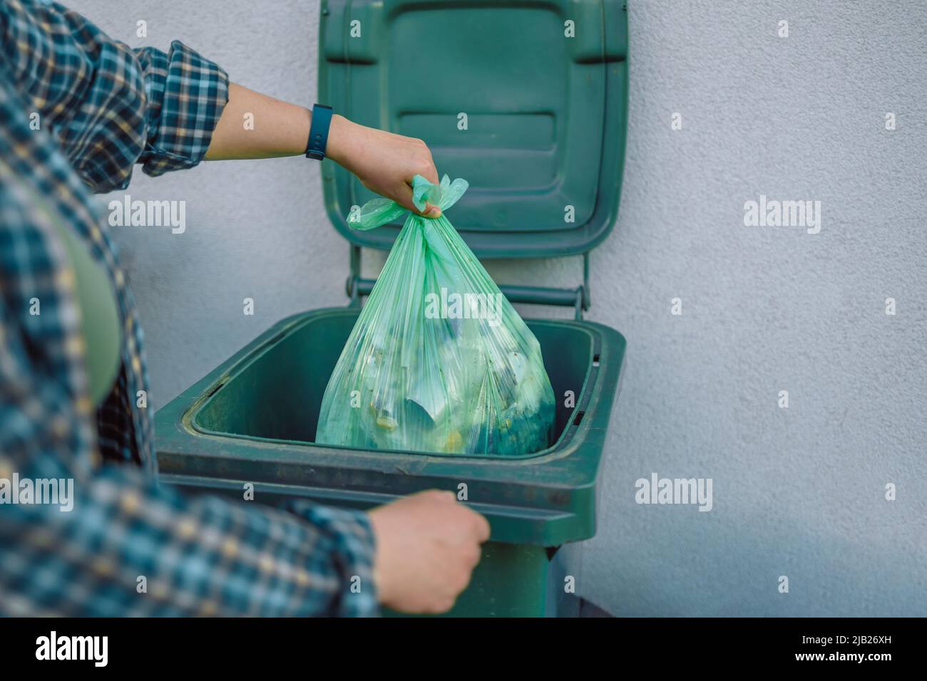 European 30s woman throwing garbage into the recycling bin in the
