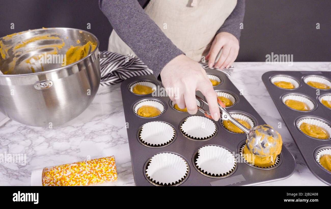 Scooping pumpkin spice cupcake batter with batter scoop into a cupcake