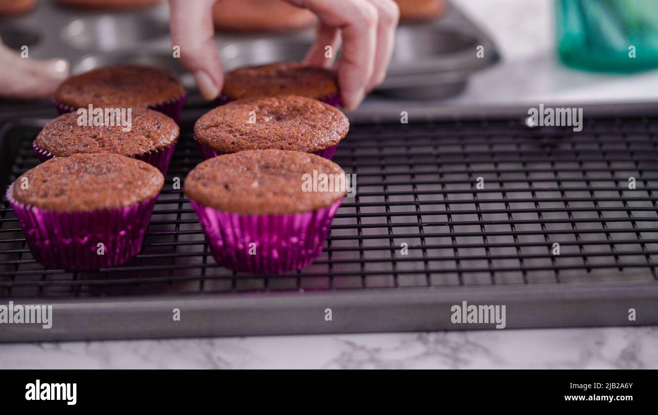 Step by step. Cooling red velvet cupcakes on a kitchen drying rack. Stock Photo