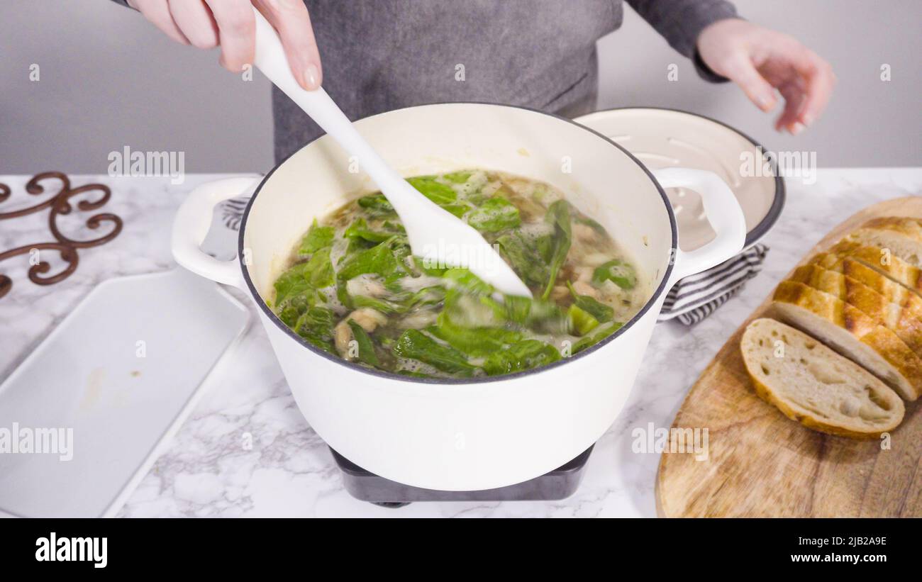 Cooking vegetarian white bean soup in cast iron dutch oven Stock Photo