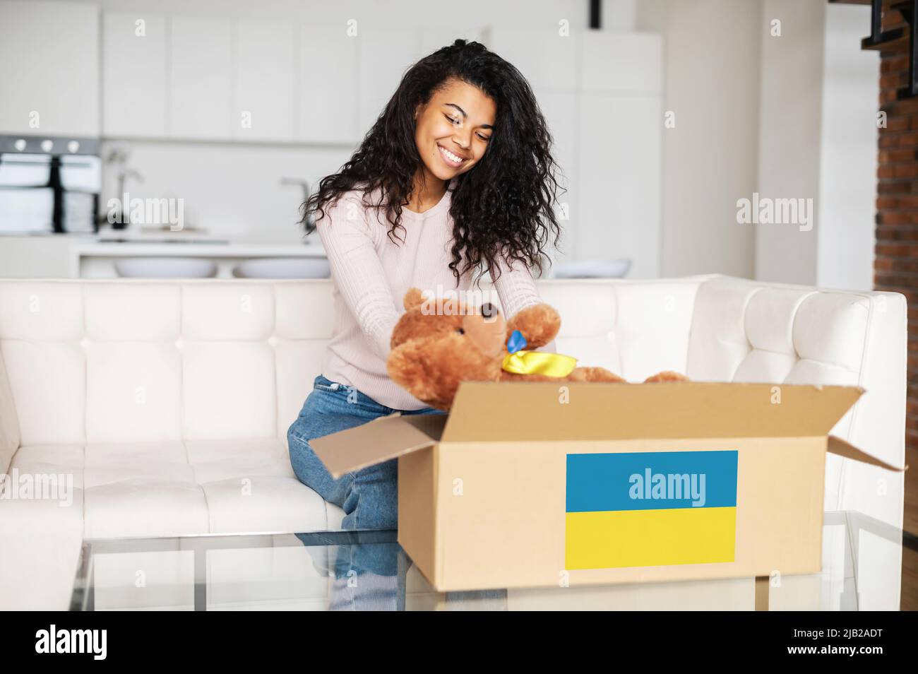 Kind smiling AfricanAmerican female volunteer sitting on a sofa