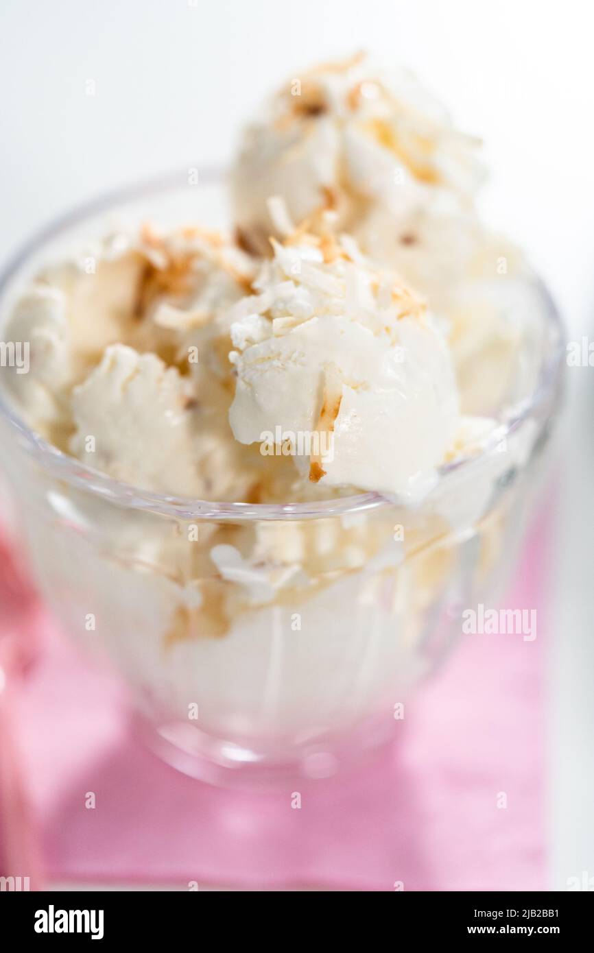 Homemade coconut ice cream garnished with roasted coconut flakes in a