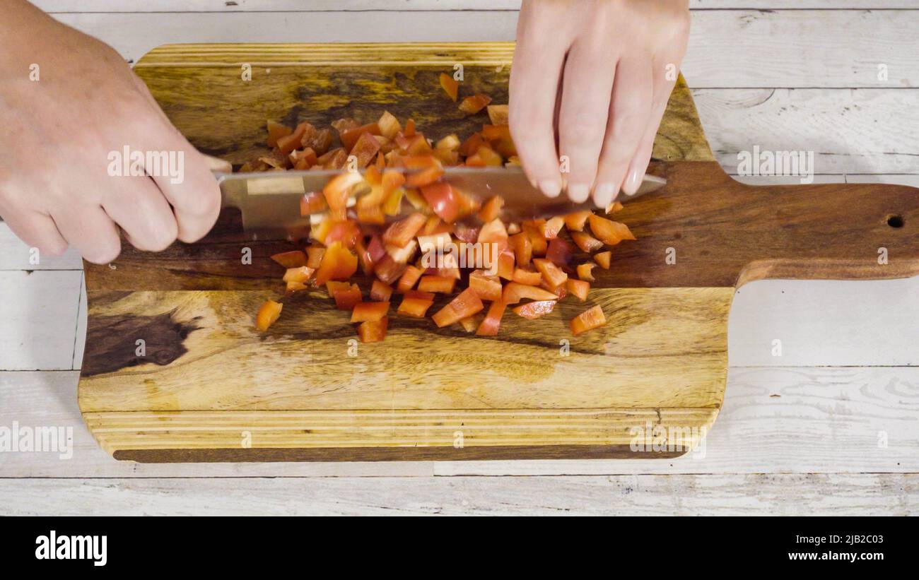 Mincing organic red bell peppers on a wood cutting board Stock Photo ...