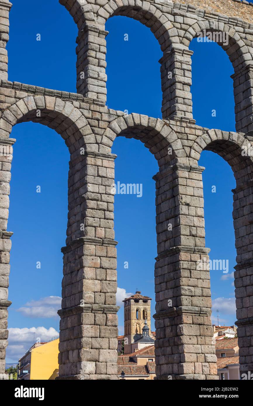 Church tower under the arch of the roman aqueduct in Segovia, Spain Stock Photo