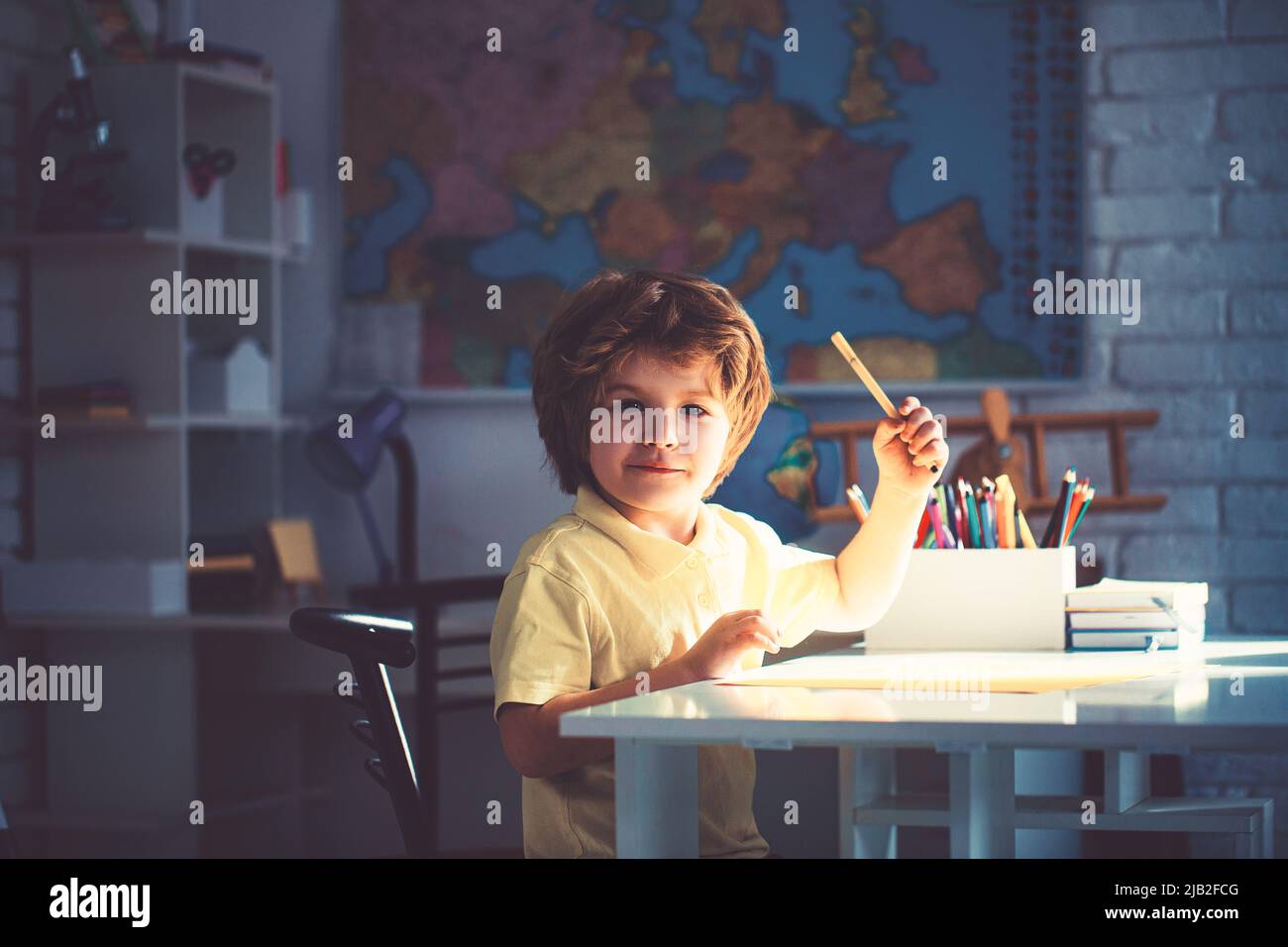 Cute little boy drawing at desk at the nursery school Stock Photo - Alamy