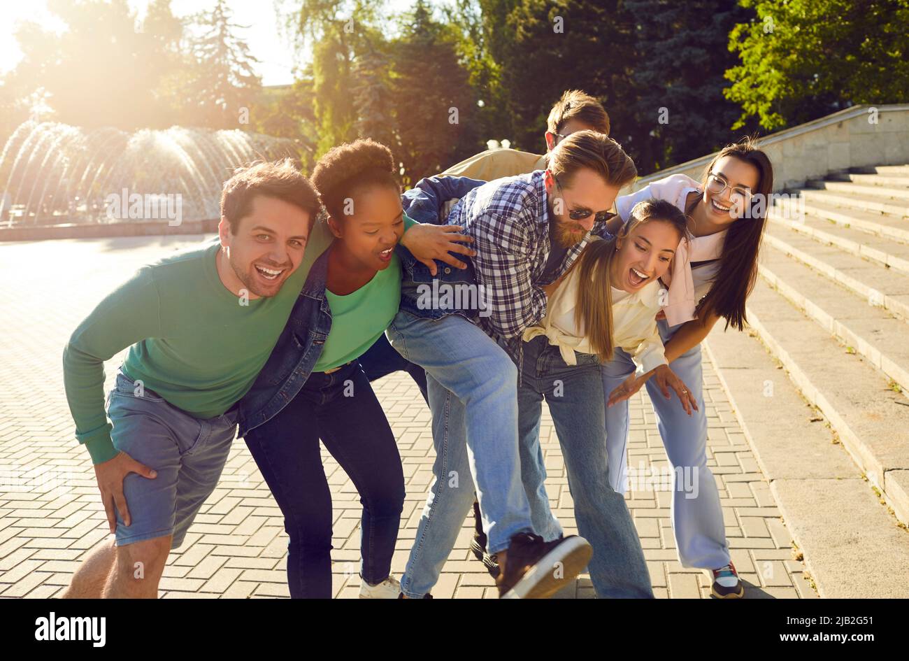 Cheerful excited men and women walking outdoors on summer day hugging ...