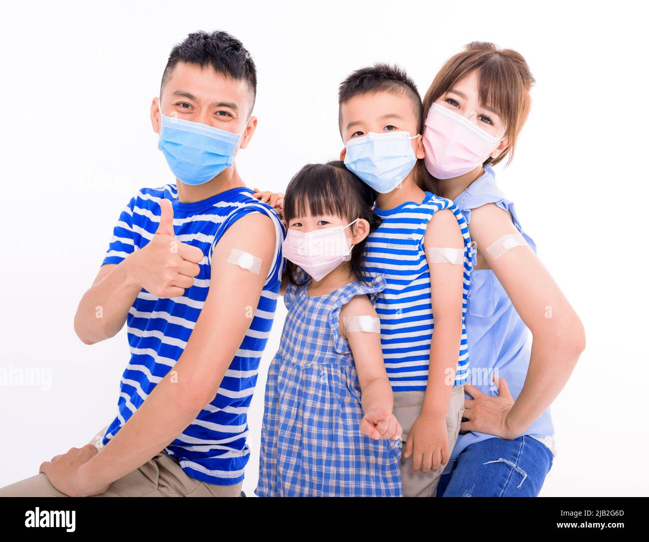 Young Family Wearing Face Masks Showing Adhesive Bandage After Coronavirus Vaccination Stock Photo