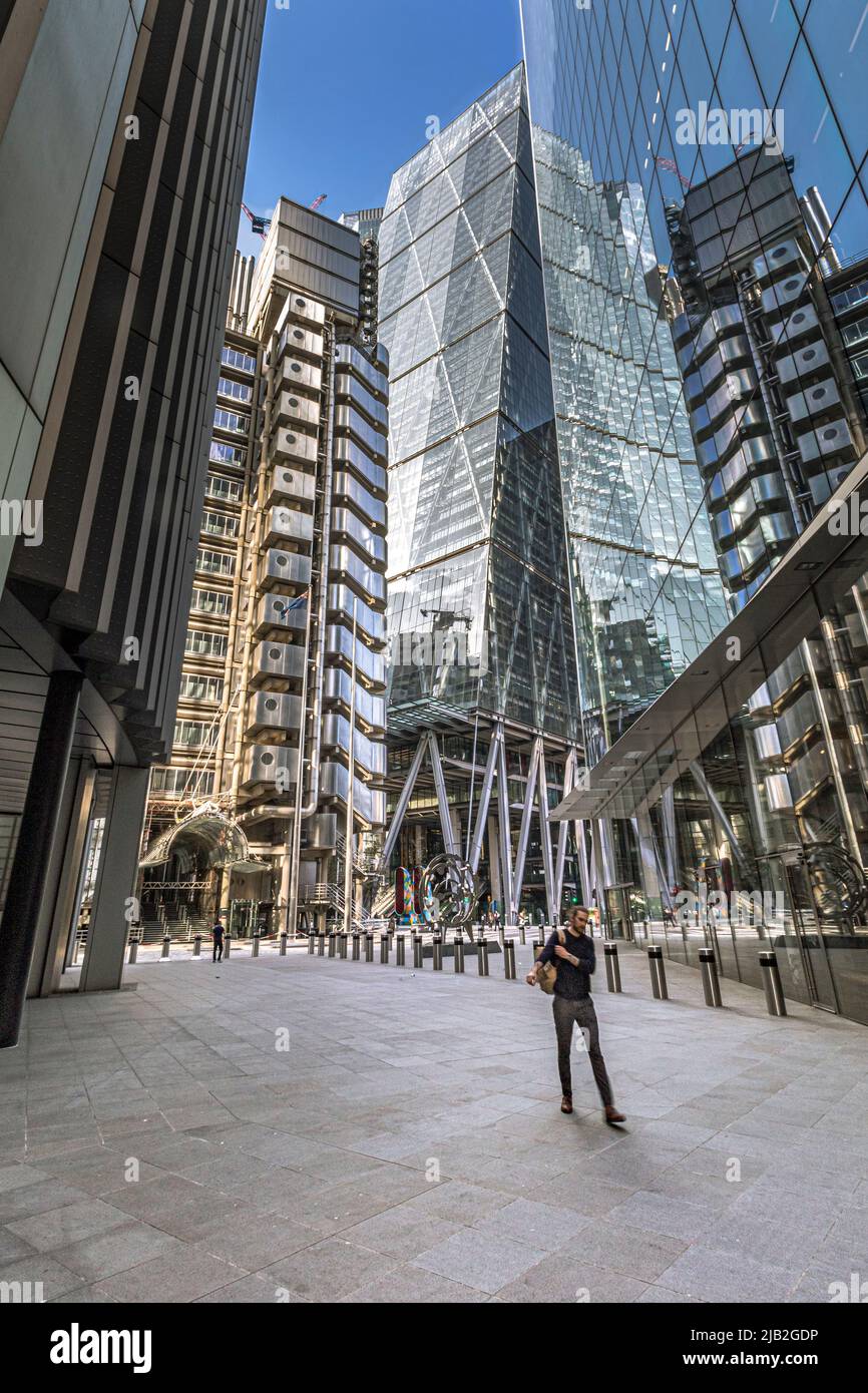 A man walks along Lime St in the City Of London with Lloyd's of London building and The Leadenhall Building in the background,  London EC3 Stock Photo