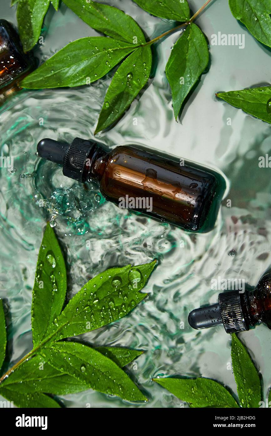 Top view Bottle with herbal serum, oil cosmetic ad, simple and natural  skincare concept, product mock up set with water ripple aside with green  leaf Stock Photo - Alamy