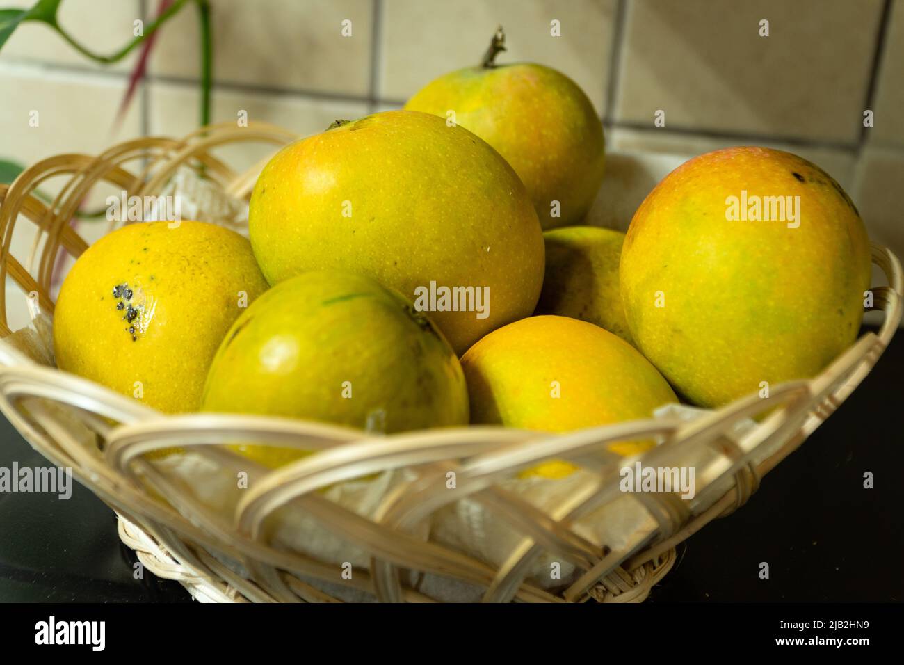 Selective focus on a group of ripe mangoes placed in a fruit basket. Closeup shot. Stock Photo