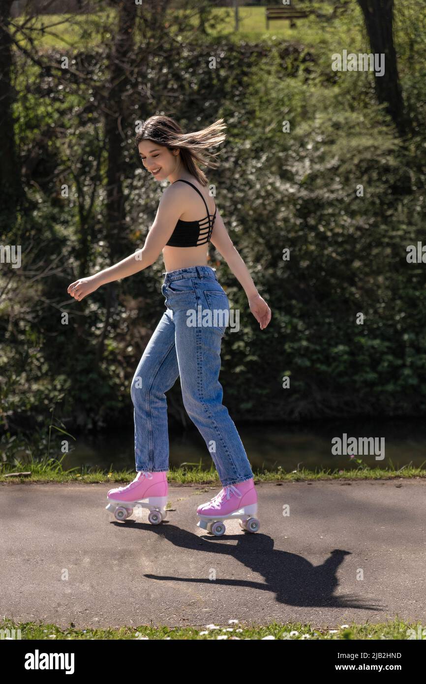 brunette woman skating in the park with pink roller skates Stock Photo