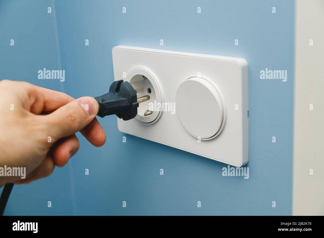 Inserting power cord receptacle in wall outlet Stock Photo