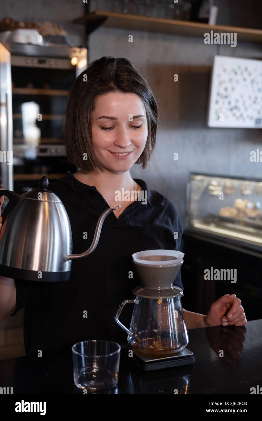 charming woman barista making filter coffee in coffee shop