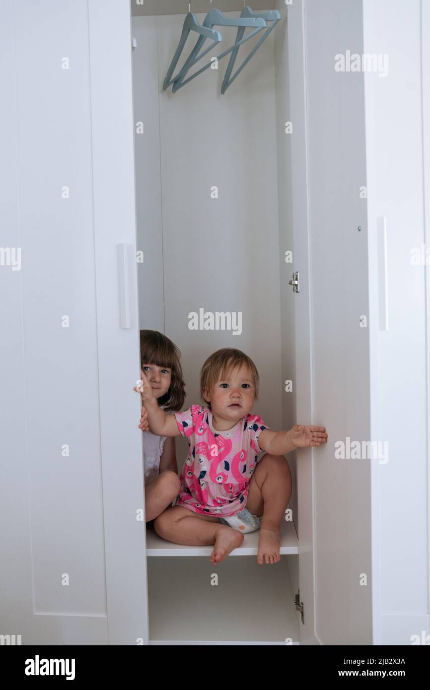 https://c8.alamy.com/comp/2JB2X3A/two-little-girls-looking-out-of-white-wardrobe-2JB2X3A.jpg