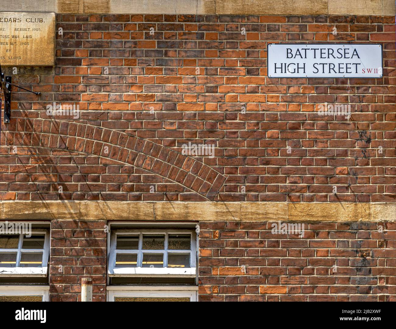 Street name sign for Battersea High Street , high on a red brick wall in Battersea , London, SW11 ,UK Stock Photo