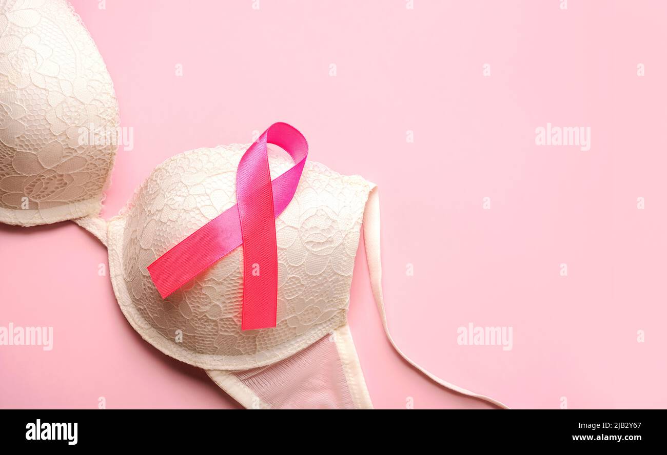 Breast cancer concept. Women's bra and pink ribbon symbol breast cancer awareness with space for text over pink background Stock Photo