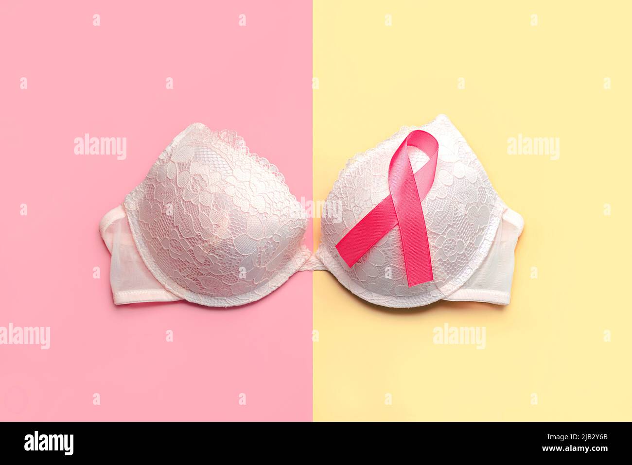 Breast cancer concept. Top view of Women's bra and pink ribbon symbol breast cancer awareness over pink and yellow background Stock Photo