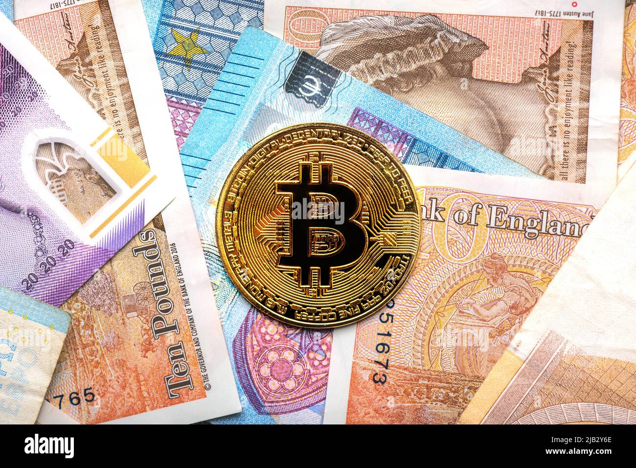 Close up of golden bitcoin coin with euro bills and British pounds. Electronic crypto currency Stock Photo